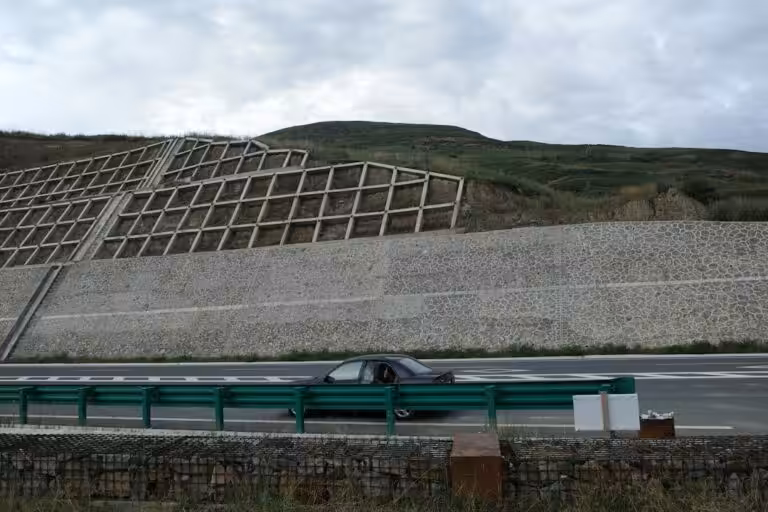 Muro di sostegno lungo una strada a protezione del versante, opera tipica della valutazione del rischio da frana