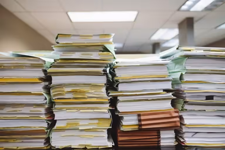 Pile di documenti cartacei e faldoni accatastati, la documentazione da raccogliere per il modello unico di dichiarazione ambientale MUD