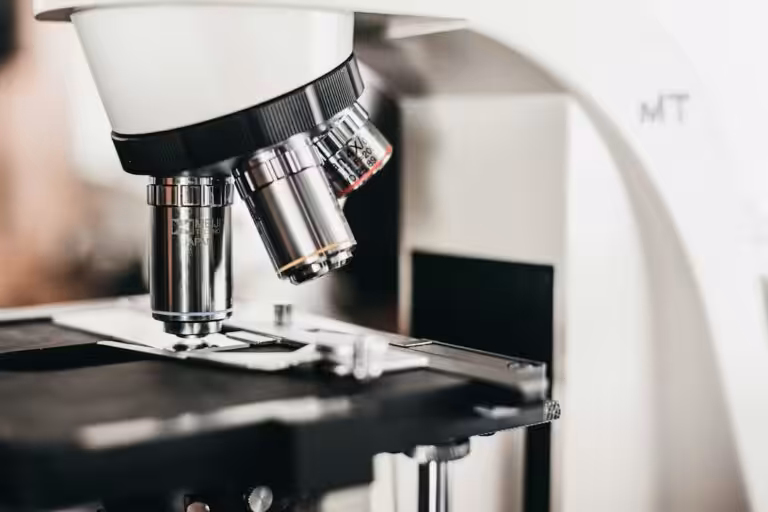 Microscopio ottico con obiettivi multipli sopra il piano portaoggetti, strumentazione del laboratorio analisi di igiene industriale