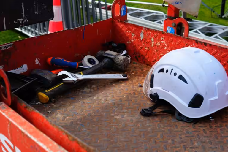 Casco protettivo bianco e attrezzi da lavoro in una cassetta metallica rossa, dotazione per la sicurezza sul lavoro in azienda