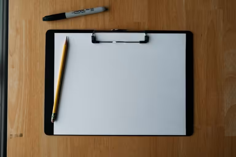 Clipboard con foglio, matita e penna su un piano di legno, strumenti per la valutazione dei rischi aziendale