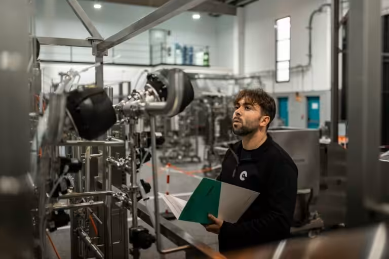 Tecnico con documentazione tecnica in mano verifica un impianto industriale, attività tipica di un sistema di gestione ISO
