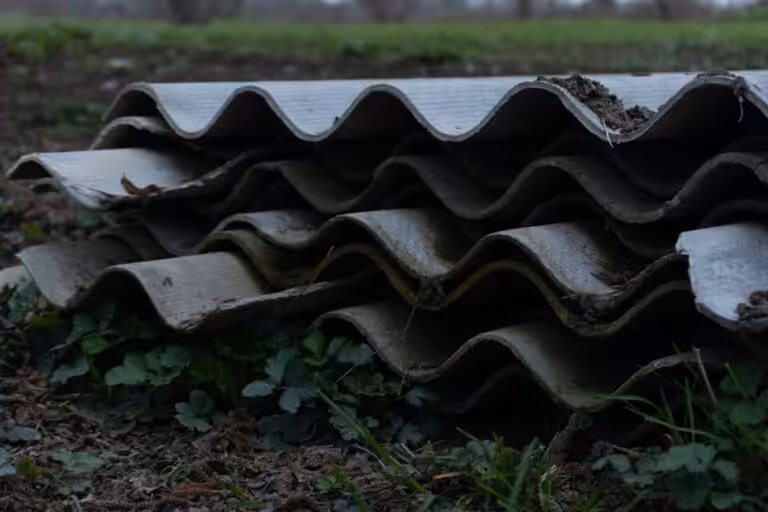 Pila di lastre ondulate in cemento-amianto deteriorate, materiale contenente amianto