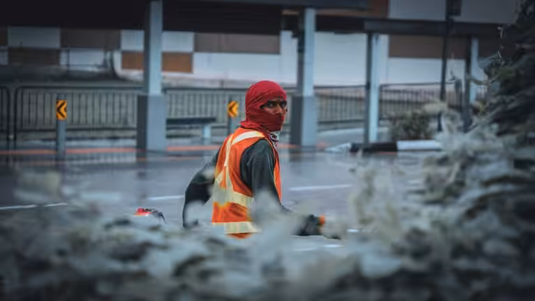 Lavoratore all'aperto con giacca e berretto in una giornata fredda e umida: rischio freddo sul lavoro