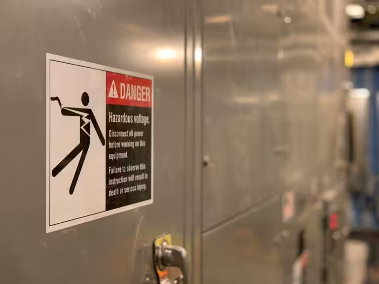 Cartello di pericolo tensione elettrica su un quadro: segnaletica di sicurezza sul lavoro